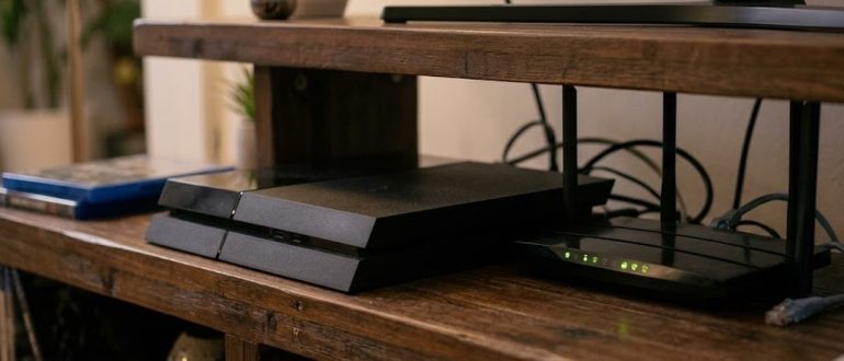 Игровая консоль PS4 и роутер с подключённым сетевым кабелем
