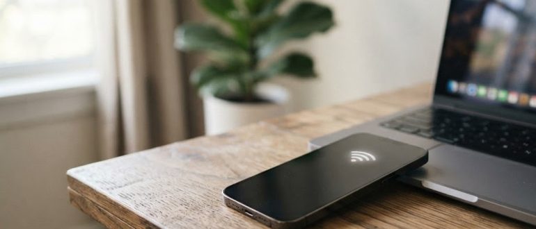 Смартфон рядом с ноутбуком на рабочем столе раздаёт интернет